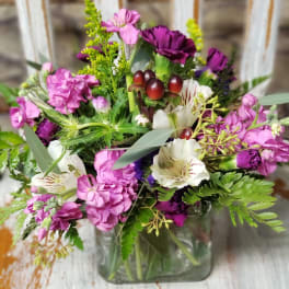 Pink and purple mixed bouquet in a square glass vase
