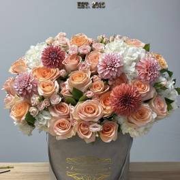 Peach and pink roses with white hydrangeas in a gray hatbox