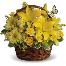 Yellow flowers arranged in a wicker basket with a butterfly decoration