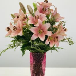 Pink lilies arranged in a pink glass vase