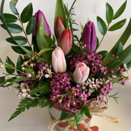 Pink and purple tulips in a striped vase with small blossoms
