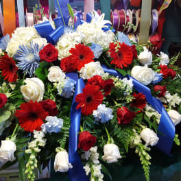 Large floral spray with red, white, and blue flowers and a blue ribbon