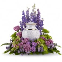 Lavender roses and purple flowers arranged around a white urn