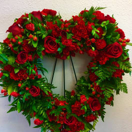 Heart-shaped wreath of red roses and carnations on a stand
