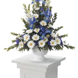 Tall blue and white floral arrangement in a white urn on a pedestal