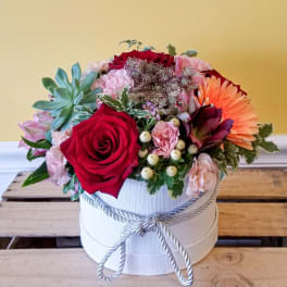 Mixed flower arrangement in a white round box with a rope bow