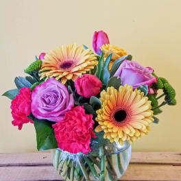 Mixed bouquet of pink and lavender flowers in a glass vase
