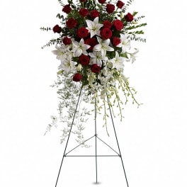Standing floral spray of red roses and white lilies on an easel