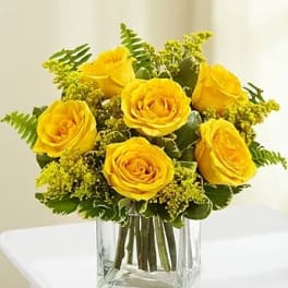 Yellow roses arranged in a clear square glass vase
