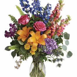 Colorful bouquet with roses, lilies, hydrangea, and snapdragons in a glass vase