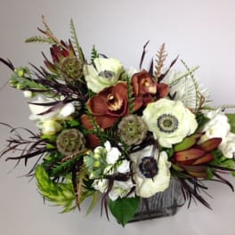 Mixed floral arrangement with white and rust blooms in a square vase