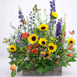 Mixed bouquet with sunflowers, orange roses, and purple blooms in a wooden box