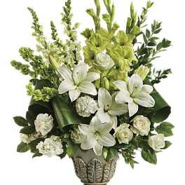 White lilies and roses in a decorative pedestal vase with green accents