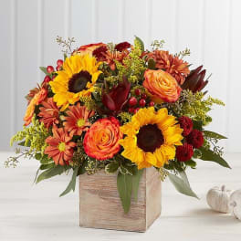 Autumn bouquet with sunflowers, roses, and mums in a wooden box