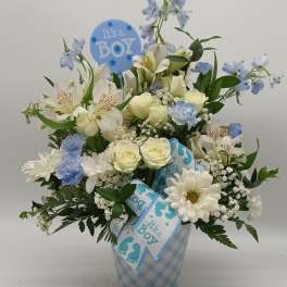 Blue and white flower arrangement in a checkered vase with a baby boy pick