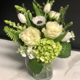 White and pale green floral arrangement in a glass vase