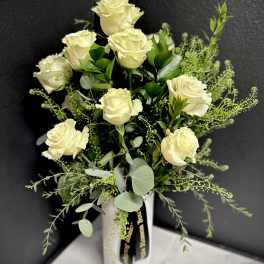 Cream roses in a white vase with airy greenery