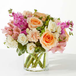 Bouquet of peach and white roses with pink flowers in a clear glass vase