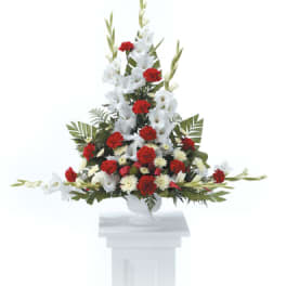 Tall red and white floral spray in a white pedestal vase