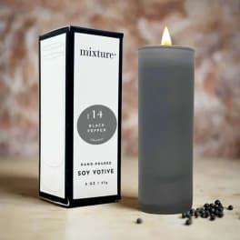 Gray soy votive candle beside its box with peppercorns