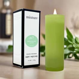 Green votive candle beside its retail box