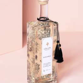 Clear glass bottle with gold cap and black tassel label