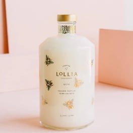 White bottle of Lollia bath product with gold cap and bee illustrations