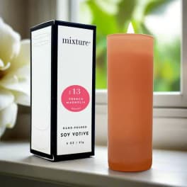 Orange votive candle beside its boxed packaging