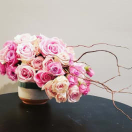 Pink and white roses in a ceramic vase with curly branches