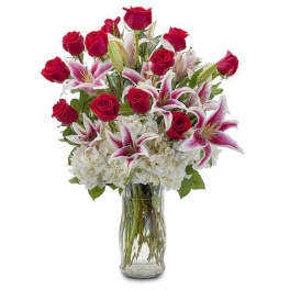 Red roses and pink lilies arranged in a clear glass vase