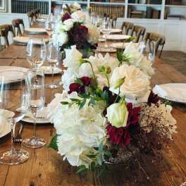 White and burgundy floral centerpieces on a long dining table