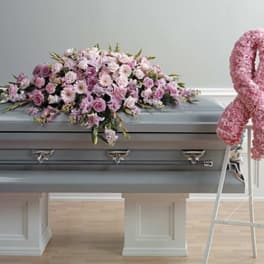 Pink floral casket spray on a gray casket