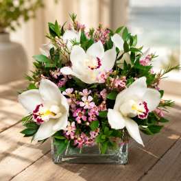 White orchids and pink filler flowers in a clear glass vase