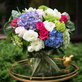 Bouquet of hydrangeas and roses in a glass vase with a ribbon
