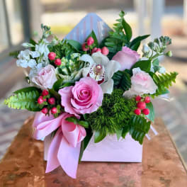 Pink and white floral arrangement in a white box with a pink ribbon