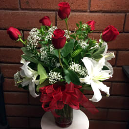 Bouquet of red roses and white lilies in a glass vase with a red ribbon