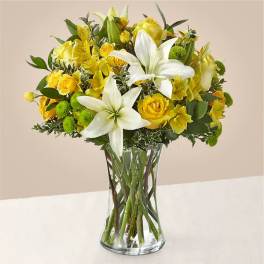 Yellow roses and white lilies in a clear glass vase