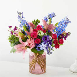 Bouquet of pink and blue flowers in a pink glass vase