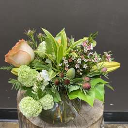 Mixed bouquet in a glass vase with peach roses and green blooms