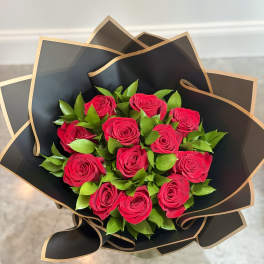 Bouquet of hot pink roses wrapped in black paper with gold trim