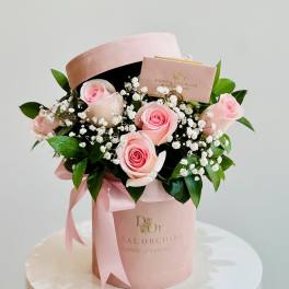 Pink roses with baby's breath in a pink hatbox with ribbon