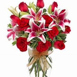 Bouquet of red roses and pink lilies in a clear glass vase