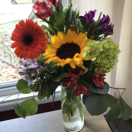 Mixed bouquet with sunflowers, gerbera daisies, and alstroemeria in a glass vase
