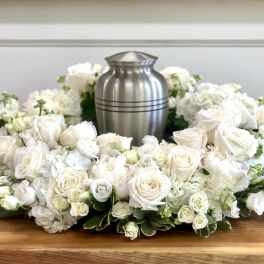 White rose and hydrangea funeral wreath around a silver urn