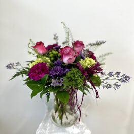 Pink roses and purple flowers in a clear glass vase