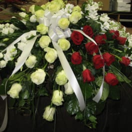 Red and white rose casket spray with white bow and trailing ribbons
