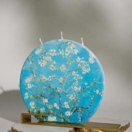 Round blue decorative candle with white blossoms on a gold stand