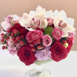 Red and pink bouquet with white orchids in a glass vase