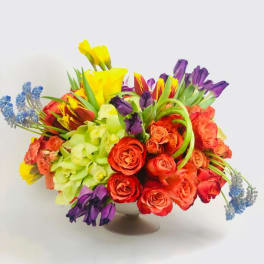 Colorful bouquet of roses, tulips, and orchids in a low vase