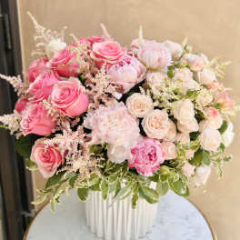 Pink and blush roses arranged in a white vase